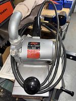 Front angle of Skil belt sander showing power cord wrapped around unit and dust bag attached.