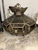 Front angle view of the octagonal bronze ceiling light fixture sitting on concrete floor, showing glass panels and bulb sockets inside