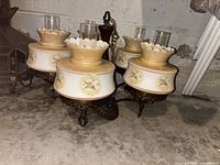 Five-bulb vintage chandelier with floral glass shades, gold and white color scheme, metal base with ornate legs, arranged on floor.