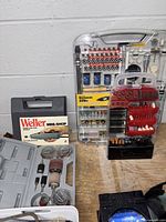 Photo showing Weller MINI-SHOP rotary tool kit with sanding drums and polishing tools, Worksmith 229-piece accessory set, and extra accessory holder containing drill bits and sanding bands.