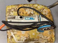 Side view of the Wolf angle grinder with visible wear on the disc and attached power cord.