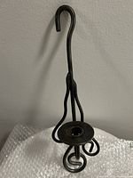 Front angled view of the black iron candle holder showing curved scroll design and candle platform.