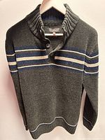Gray acrylic sweater with blue and white horizontal stripes, displayed on hangers against a white background, showing front views including ribbed collar with buttons, ribbed cuffs and bottom hem.