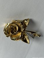 Close-up front view showing detailed flower petals and leaves in gold-tone metal.