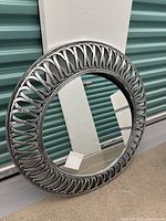 Front view of the round mirror with detailed design on the gray plastic frame and reflective mirror surface.