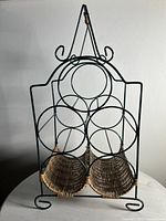 Front view of a vintage style wine rack made of green metal rings designed to hold bottles and a wicker basket base