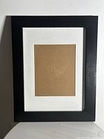 Front view of the picture frame showing a black wood frame with white matting and cardboard placeholder inside.