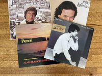Four vinyl LP albums arranged on a wooden surface showing cover artwork for Engelbert Humperdinck Christmas Tunes, Julio Iglesias, Alain Morisod Sweet People, and Jane Olivor Closing Business.