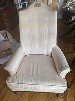 Front view of a light cream antique armchair with button-tufted backrest and padded armrests
