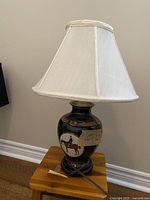 Full view of the lamp with horse design on base and white fabric shade
