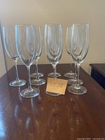 Front view of 6 champagne flutes showing shape and clarity of glass on a wooden surface.