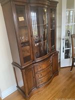 Photo of wooden dining cabinet with glass doors on top hutch and closed buffet below