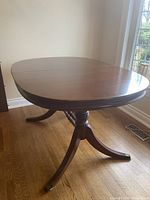 Full view of the oval Duncan Phyfe style dining table in medium-dark wood finish