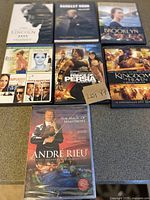 Top view of DVD cases arranged on table showing cover art of 8 DVD titles including movies and music concert.