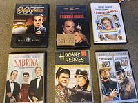 Six DVD cases with cover art featuring 'Goldfinger', 'The Russia House', 'I Remember Mama', 'Sabrina', 'Hogan's Heroes', and 'Pale Rider'.