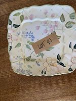 Top view of square ceramic deviled egg tray with hand painted floral designs and divided sections for deviled eggs. Tag marked LOT 81 on top.