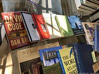 Books laid out on glass table, showing front covers of various titles including The Da Vinci Code and others