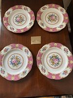 Four Royal Doulton Lady Carlyle 7.5 inch dessert or salad plates arranged on a wooden surface showing top decorative floral pattern with pink and gold border.