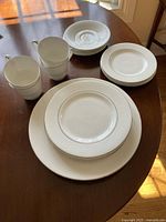 Full set on table showing plates and cups with embossed lace pattern and gold trim