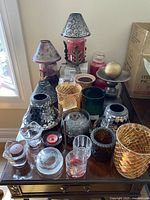 Image showing assortment of candle holders, candle lampshades, and candle accessories of various colors and materials placed on a wooden surface.