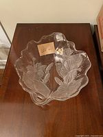 Top-down photo of a vintage Mikasa glass serving bowl showing embossed floral and leaf pattern and scalloped edges.