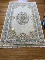 Full view of the rectangular wool rug with floral and geometric bordering and central medallion on wooden floor.