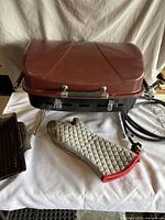 Portable propane camping BBQ grill with attached hose and brown lid, quilted oven mitt placed in front.