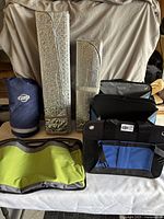 Photo showing all items together including two Thule storage boxes, rolled blue Nissan blanket, and two silver sun blocker screens.