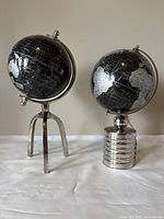 Both black globes side by side on a white surface against a plain background, showing overall size, color and style