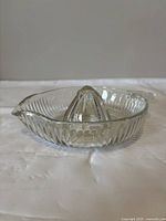 Side angle of first clear glass hand juicer showing ribbed detail and pouring lip