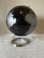 Front angle of large black and silver globe showing parts of Africa and Europe continents, centered on Atlantic Ocean.