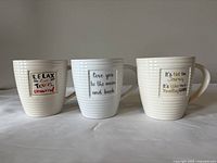 Set of three ceramic mugs with different slogans, arranged side-by-side showing the front of each mug.