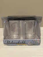 Front view of the unopened box containing 4 clear polycarbonate cups labeled as unbreakable.
