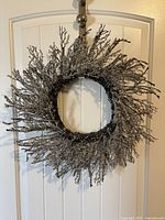 Front view of silver sparkle wreath hanging on door, showing full circular shape and glitter accents on twig branches.