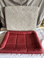 Red animal bed with padded base, cushioned edges, in good condition
