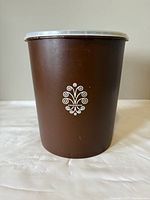 Front view of large brown Tupperware container showing white Harvest emblem.