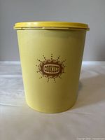 Front view of large yellow Tupperware cookie container with "COOKIES" printed in brown.