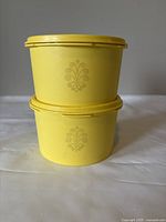 Two stacked yellow Tupperware containers showing the Harvest pattern on the sides