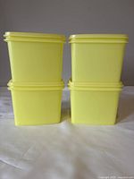 Four green square Tupperware containers stacked in two columns.