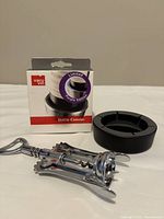 Black wine bottle coaster beside a silver corkscrew