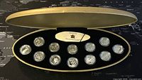 Open presentation box showing 12 Canadian silver proof quarter coins each in clear protective capsules.