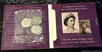 Open keepsake booklet showing four of the coins on one page, with text and photos about Queen Elizabeth II's Golden Jubilee on the opposite page.