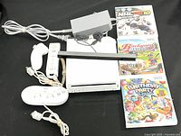 Full lot of Nintendo Wii console with accessories and games shown on black background.