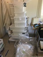 Stack of numerous clear plastic storage bins with lids in various sizes from small to large, some labeled 15 quart and unlabeled larger bins approximately 60 quart.