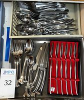 Drawer view with two trays holding assorted forks, spoons, knives and small cocktail forks.