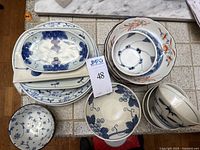 Top view of all bowls and plates showing the variety of blue and orange patterns, some marked Made in Japan.