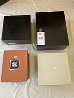 Four closed boxes containing the four tea sets, showing varying sizes and styles of packaging.