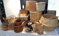 Photo showing a variety of baskets of different sizes and shapes on a table with some stacked and some standing alone.
