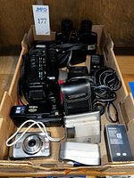 Top view of box with Fuji-8 P660 camcorder, Sony Cybershot camera, battery chargers, cables, and binoculars