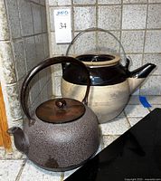 Photo of both ceramic teapot and metal tea kettle together on kitchen countertop.